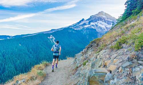 hiking man running on edge near mountain mountain