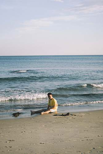 nature man sitting by the seashore during daytime ocean