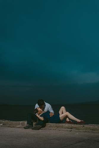 couple man kissing woman while sitting on railings during night love