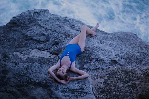 person woman lying on boulder neat water human