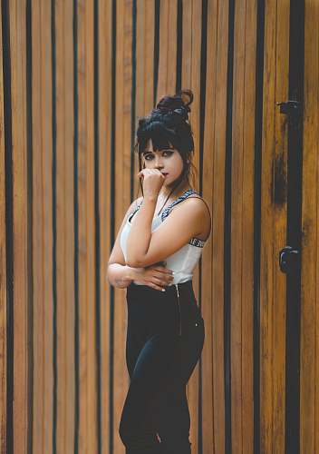 person woman standing near brown wooden wall at daytime human