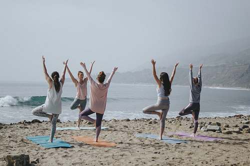 human five woman standing on seashore yoga