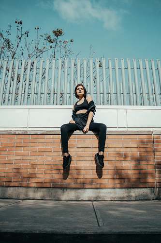 human girl sitting on brown concrete wall people