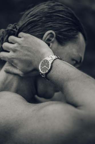 human grayscale photography of man touching his nape wristwatch