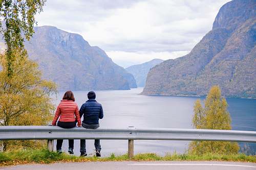 human man and woman sitting on road fence people