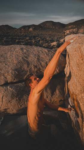 human man climbing rock outdoors