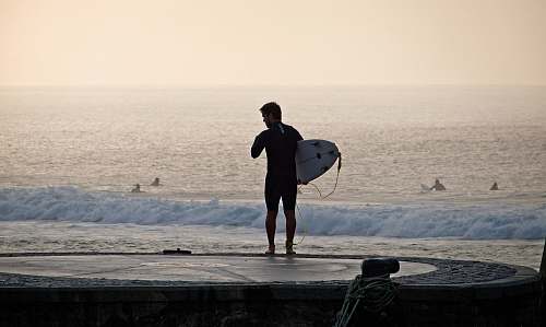 human man holding surfboard near seashore people