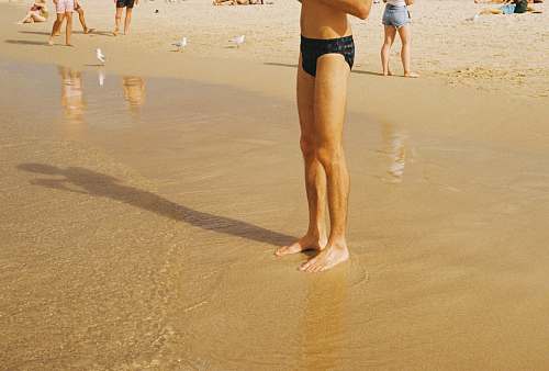 human man in black speedo standing on beach apparel