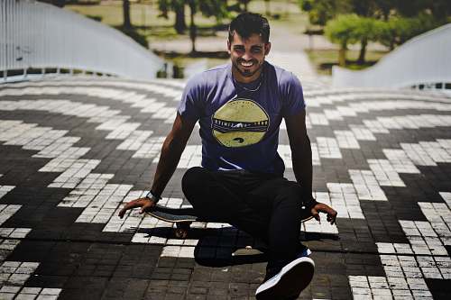 human man in gray t-shirt sitting on skateboard people
