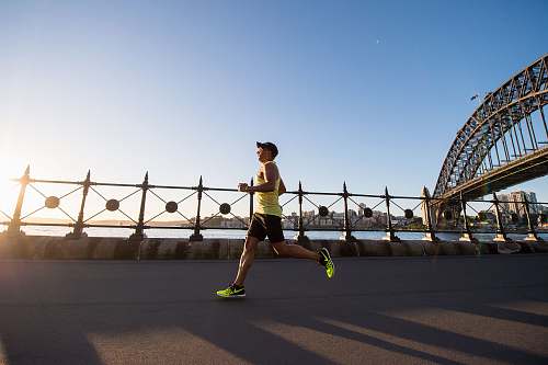 human man in yellow tank top running near shore working out
