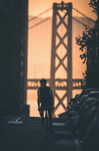 human man riding bike beside parked cars during day clothing