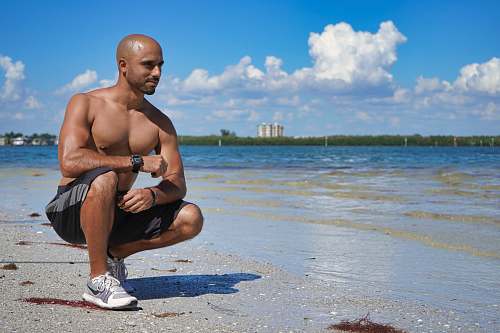 human man sitting down beside seashore shoe