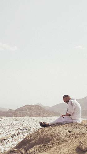 human man sitting on ground near outdoor during daytime sitting