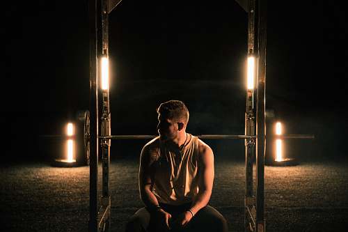 human man wearing grey tank top sitting on brown wooden bench clothing