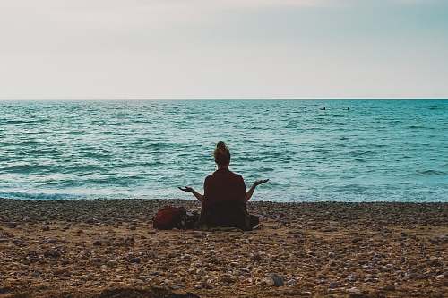 human person doing yoga on seashore during daytime people