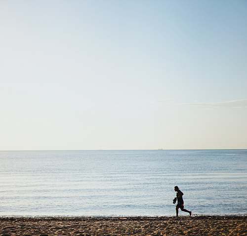 human person running on shore during daytime exercise
