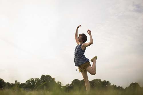 human person standing raising right leg as well as both hands apparel