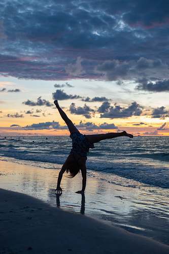 human person standing upside down on seashore sports