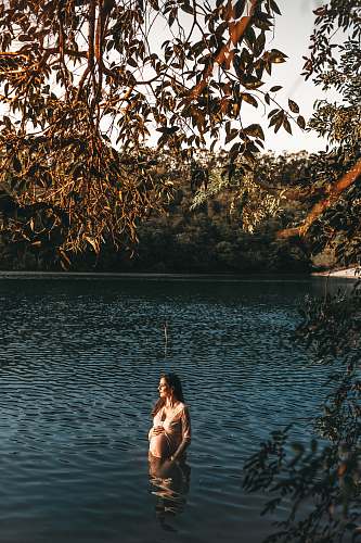 human pregnant woman standing in body of water during daytime water