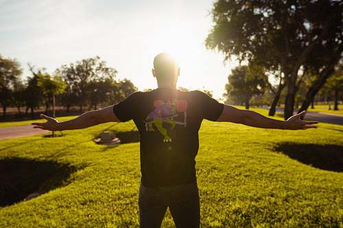grass shallow focus photo of person in black and green T-shirt plant