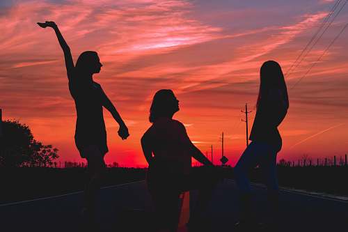 people three women posing in the middle of the road during golden hour human