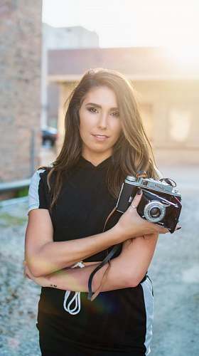 human woman in black and white t-shirt holding DSLR camera people