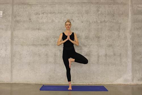 human woman in black attire doing one foot stance yoga yoga