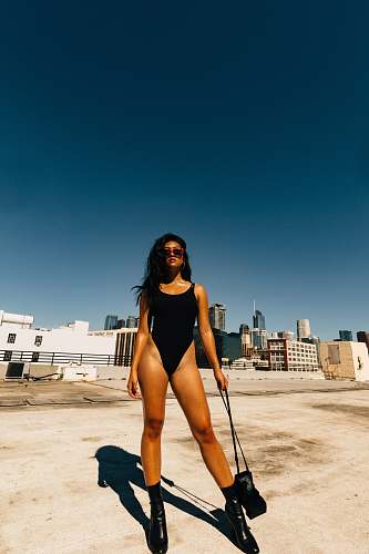 human woman in black bodysuit holding black crossbody bag people