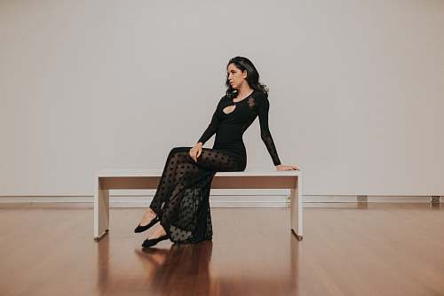 human woman in black dress sitting on bench wood