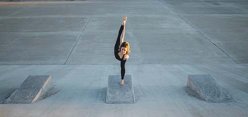 human woman in black sleeveless shirt doing yoga grey