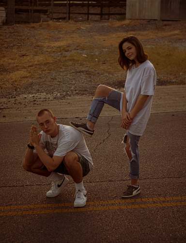 human woman in white stepping on crouching man's back apparel