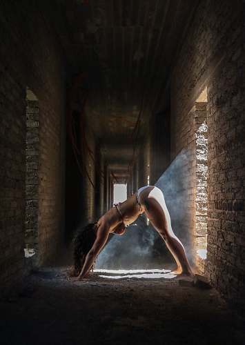 human woman leaning forward on ground inside brick hallway corridor