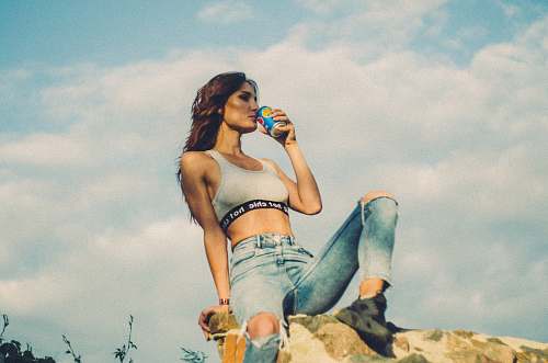 human woman sitting on rocky hill drinking soda can during daytime people