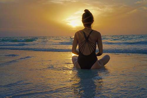 human woman sitting on shore during golden hour exercise