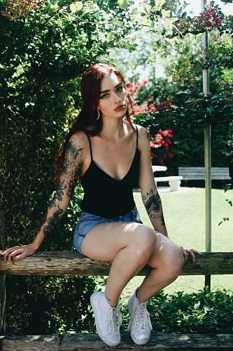 human woman sitting on wooden bench beside plant people
