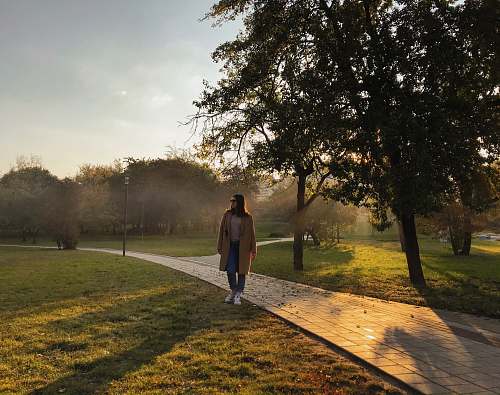 human woman standing near pathway during daytime plant