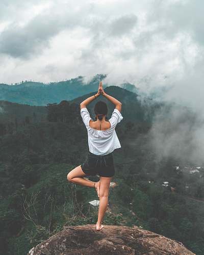 human woman standing on rock facing forest apparel