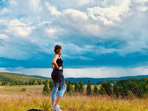 human woman wearing black and teal ju7mp suit walking on grass field apparel