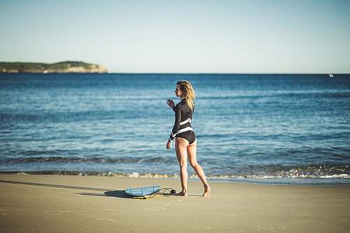 human woman wearing black one-piece swimsuit walking on shore apparel