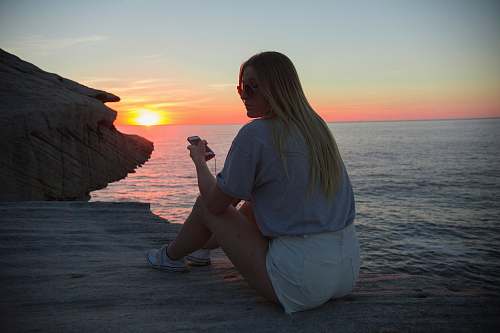 human woman wearing grey blouse sitting near the body of water apparel