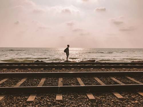 railway boy standing on shore near waves train track