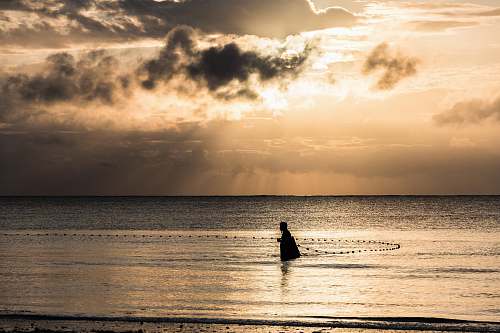 fishing person on ocean during sunrise beach