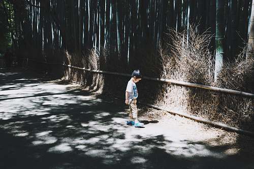 child boy wearing white top standing on gray concrete floor kid