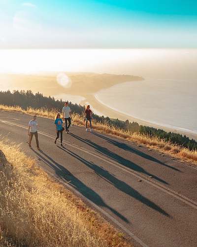 jogging four men and women walking on roadway near body of water fitness