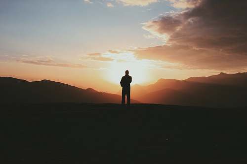 sunrise silhouette photo of man standing on mountain during golden hour himalayas