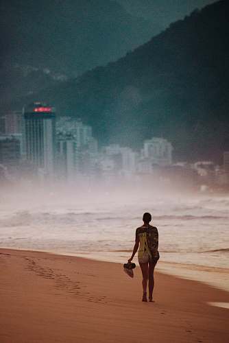 person girl walking on seashore across city building human