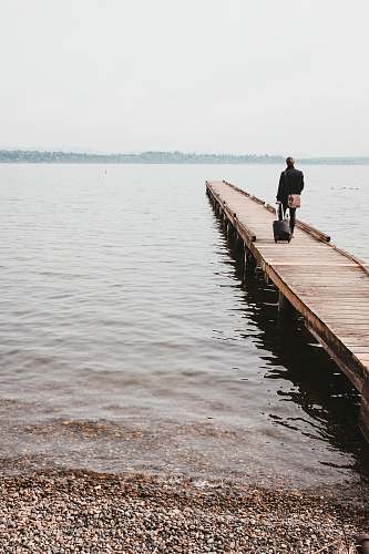 pier person walking on dock while towing luggage bag dock