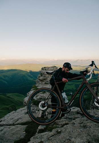 machine man carrying road bike at top of mountain bicycle