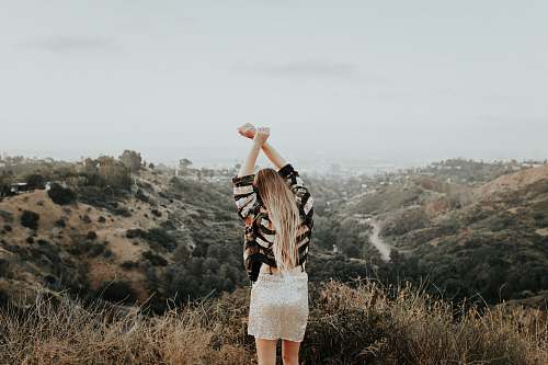 blonde woman standing on top of mountain female