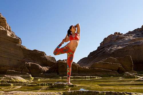 bikini woman standing in one leg beside rocks at daytime clothing